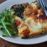 baked tomato spinach and mozzarella tortilla on a plate with salad